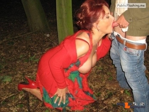 Busty mature redhead in red dress in on knees and sucking dick in public